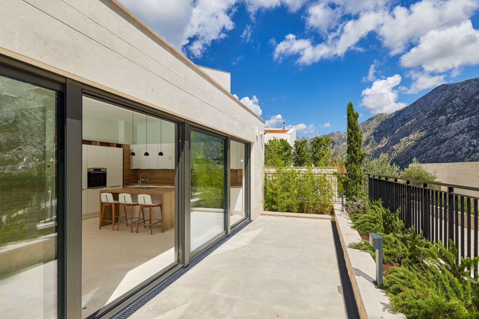 Karadağ, Prčanj’deki modern villanın terası, dağ manzaralı ve panoramik camlı mutfağa açılıyor.
