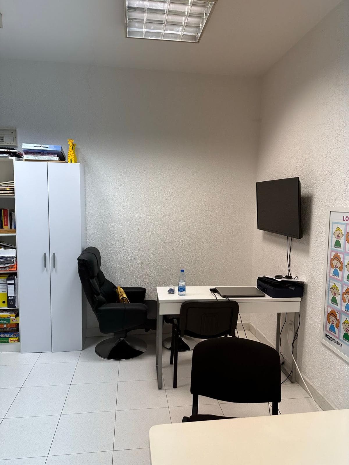 Büroraum in Bar, Montenegro: Arbeitsplatz mit weißem Tisch, schwarzem Stuhl, Schrank und TV an der Wand.