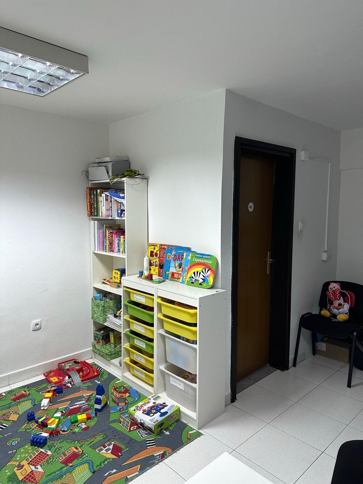 Kinderspielbereich in einem Gewerberaum in Bar, Montenegro: Regale mit Spielzeug und ein Teppich mit Straßen.