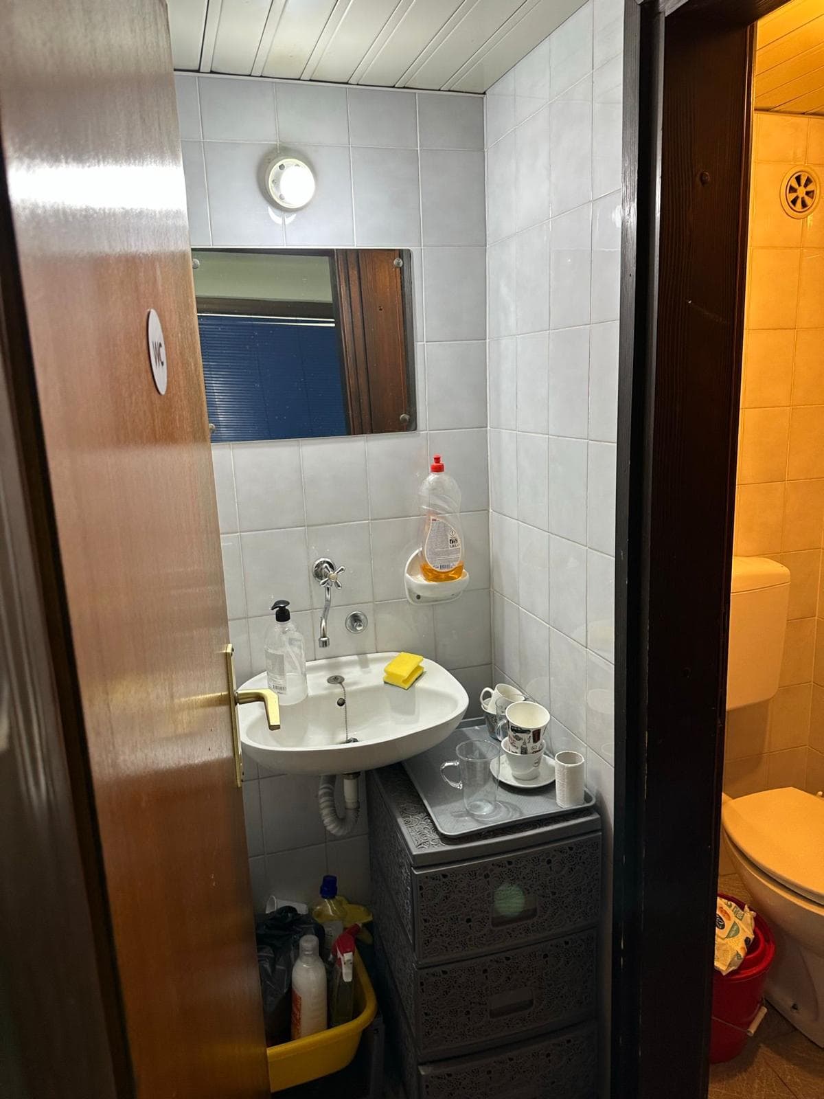 Badezimmer in einem Gewerberaum in der Stadt Bar, Montenegro: weiße Fliesen, Waschbecken und Toilette, Innenansicht.