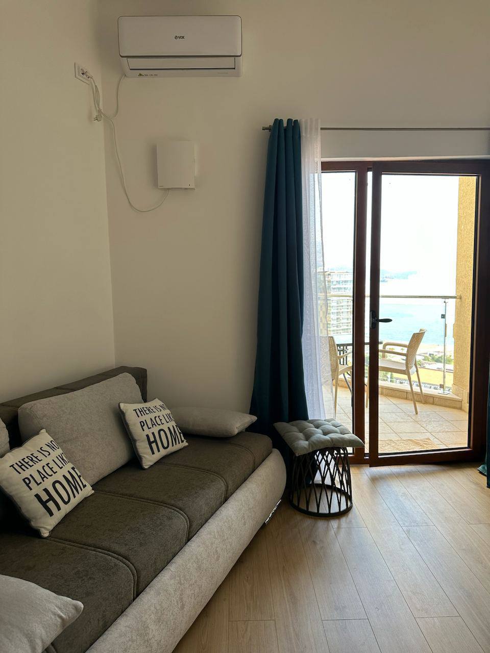 Dnevna soba u stanu u Bečićima, Crna Gora: sivi sofa, izlaz na terasu sa pogledom na more i moderna klima.