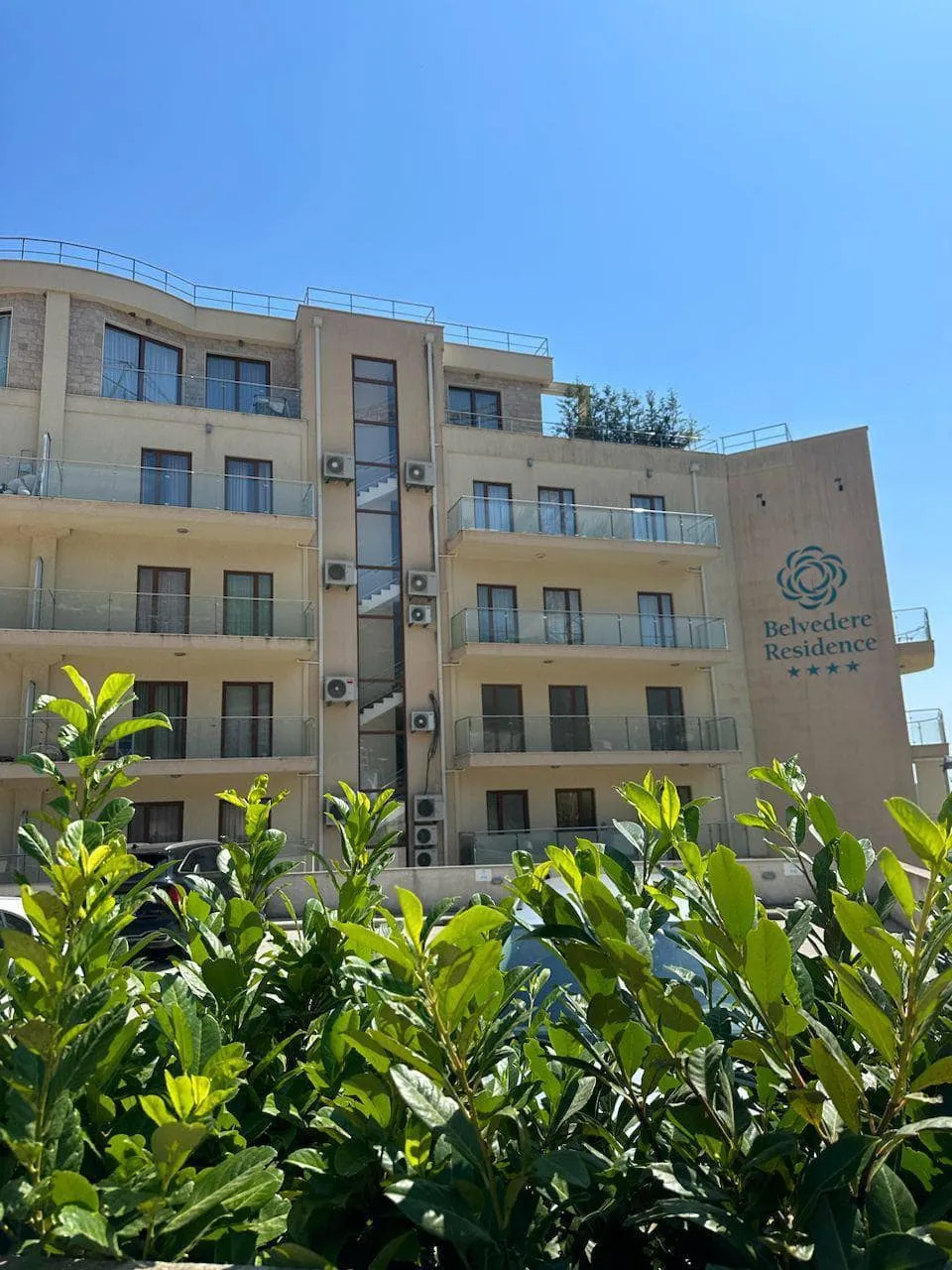 Facade of the Belvedere Residence residential complex in Bečići, Montenegro: a modern building with balconies and glazing.