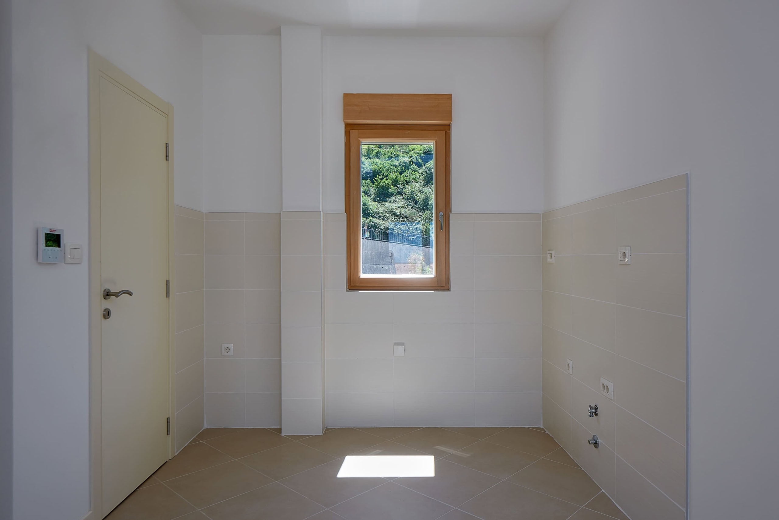 Bright kitchen in an apartment in Dobrota, Montenegro: wall tiles, wooden window with mountain view, appliance hookups.