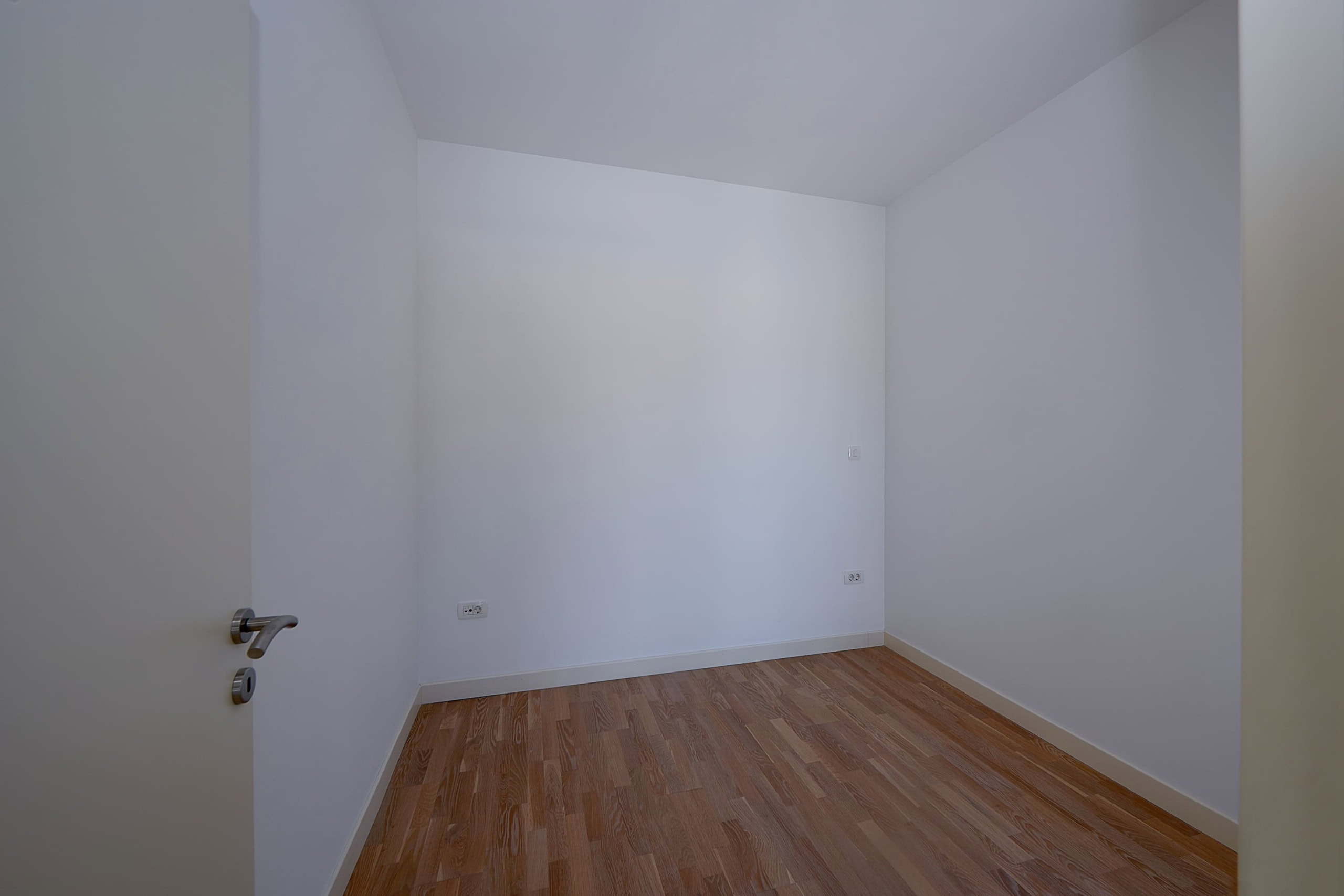 Empty bedroom with white walls and laminate flooring in an apartment for sale in Dobrota, Montenegro.