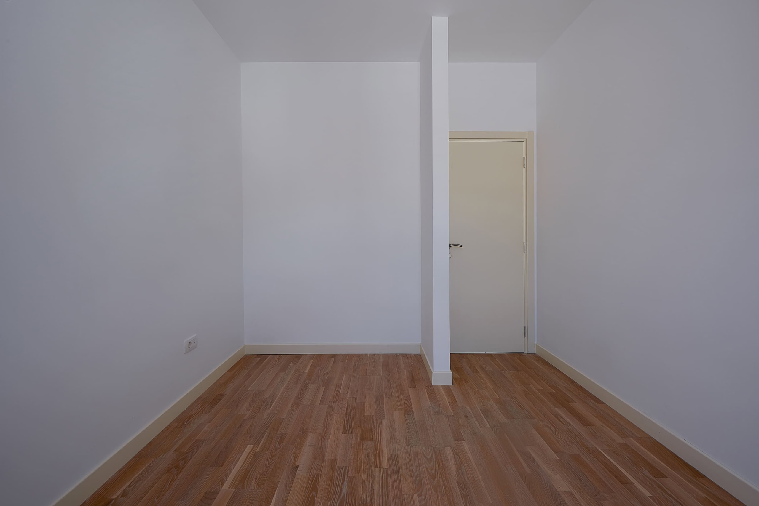 Bright empty bedroom with white walls and parquet flooring in an apartment in Dobrota, Montenegro.
