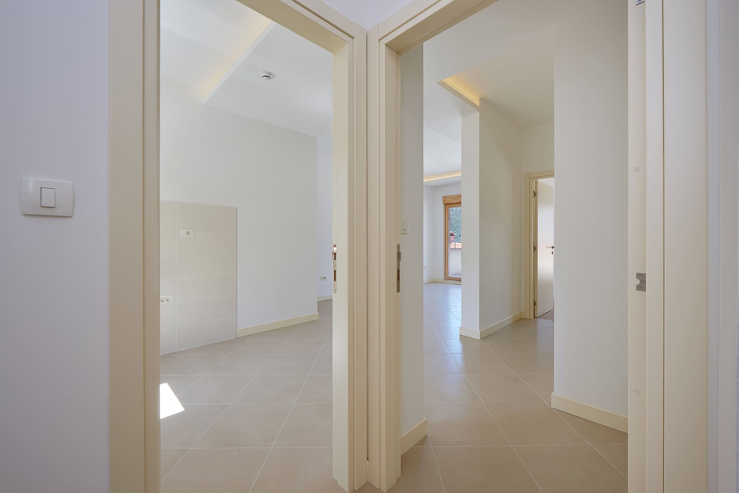 Bright apartment interior in Dobrota, Montenegro: interior doors, white walls, and tiled flooring in the hallway.
