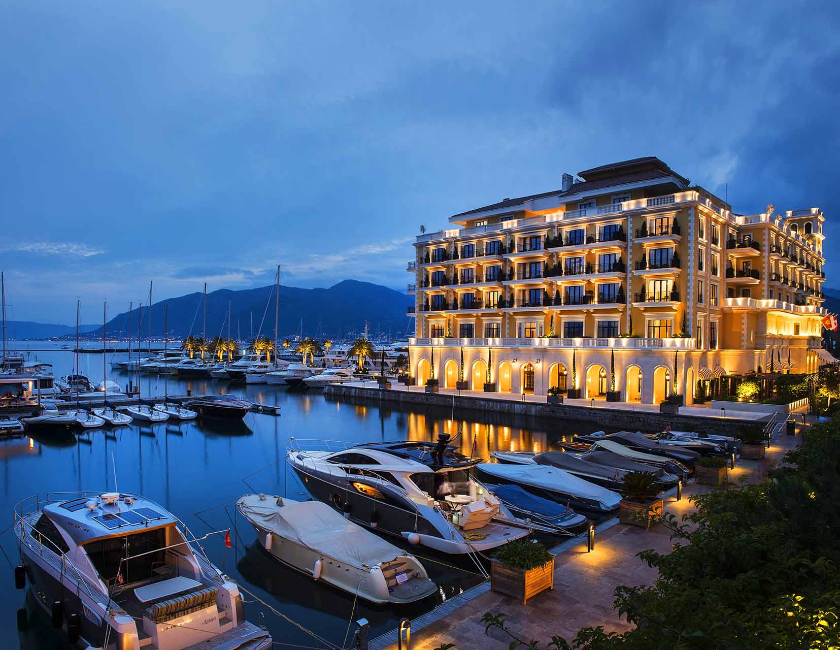 Роскошный отель Regent в марине Porto Montenegro, Тиват, Черногория: вид на здание с подсветкой и яхтенную пристань.