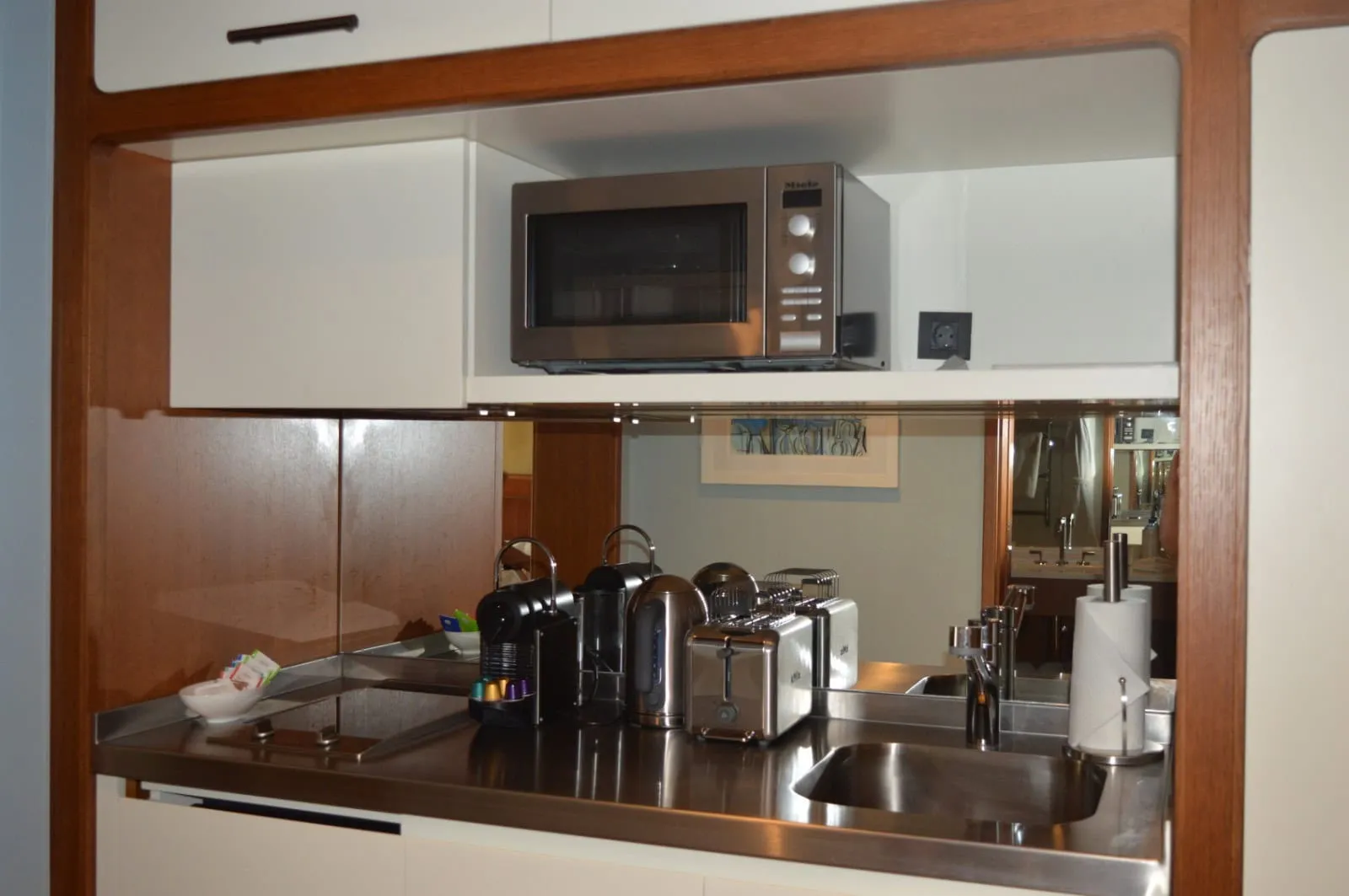 Coin cuisine dans un studio à Tivat, Monténégro : électroménager encastré Miele, évier, machine à café et grille-pain sur le plan de travail.