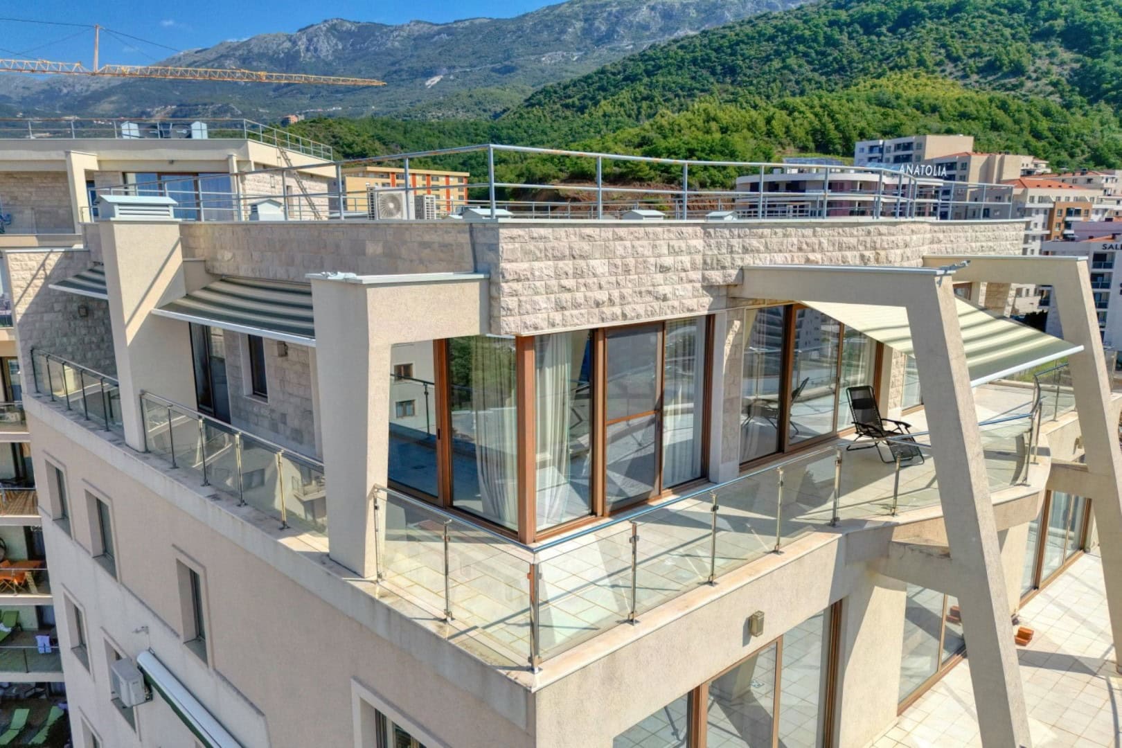 Penthaus sa panoramskom terasom i pogledom na planine u Bečićima, Crna Gora: moderan dizajn enterijera i staklene ograde.