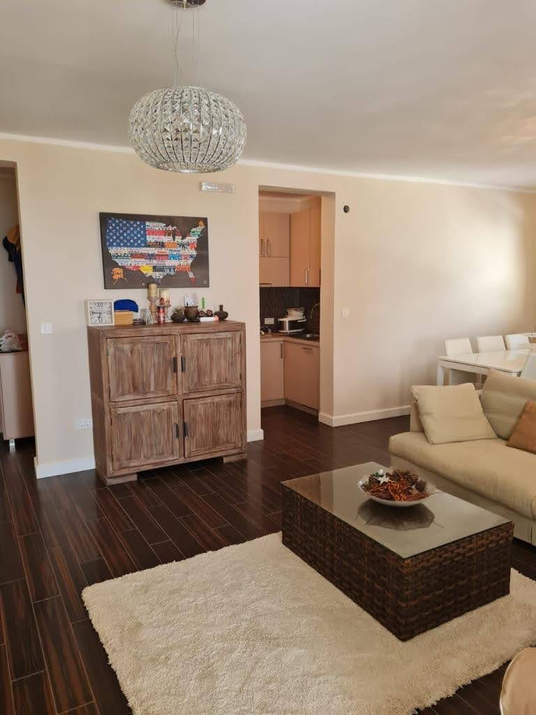 Salon z ciemną podłogą, beżową sofą i drewnianą komodą w mieszkaniu, Petrovac, Czarnogóra.