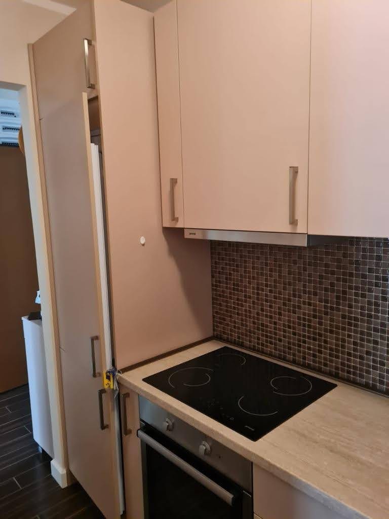 Nowoczesna kuchnia w mieszkaniu w Petrovacu, Czarnogóra: beżowe fronty, wbudowana płyta i mozaikowy backsplash.