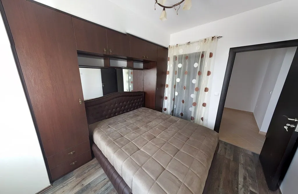 Schlafzimmer mit Doppelbett und Einbauschrank in einer Wohnung, Budva, Montenegro. Helles Interieur mit dunklen Möbeln.
