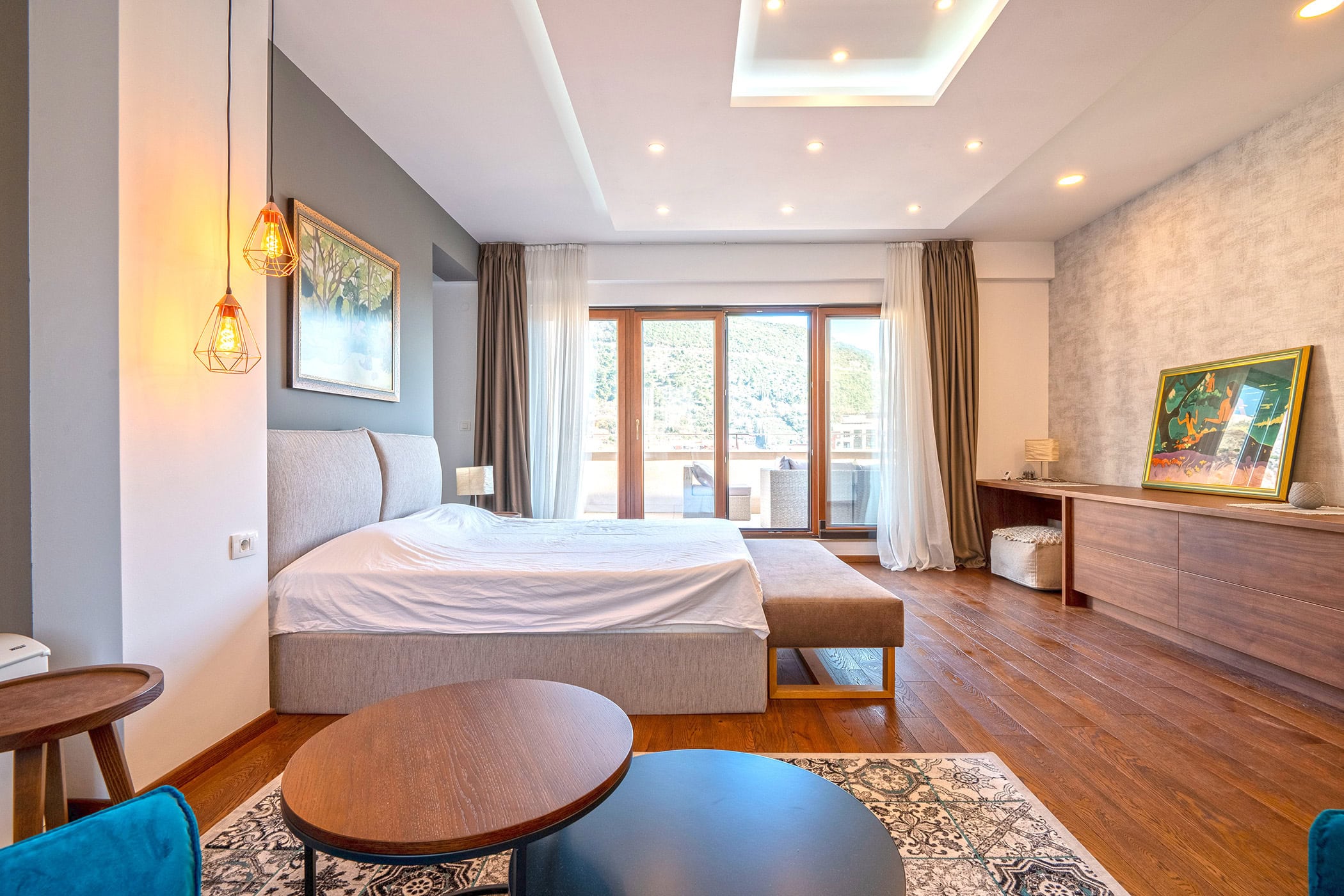 Modernes Schlafzimmer in einem Duplex in Budva, Montenegro: Doppelbett, Holzboden und Zugang zur Terrasse mit Aussicht.
