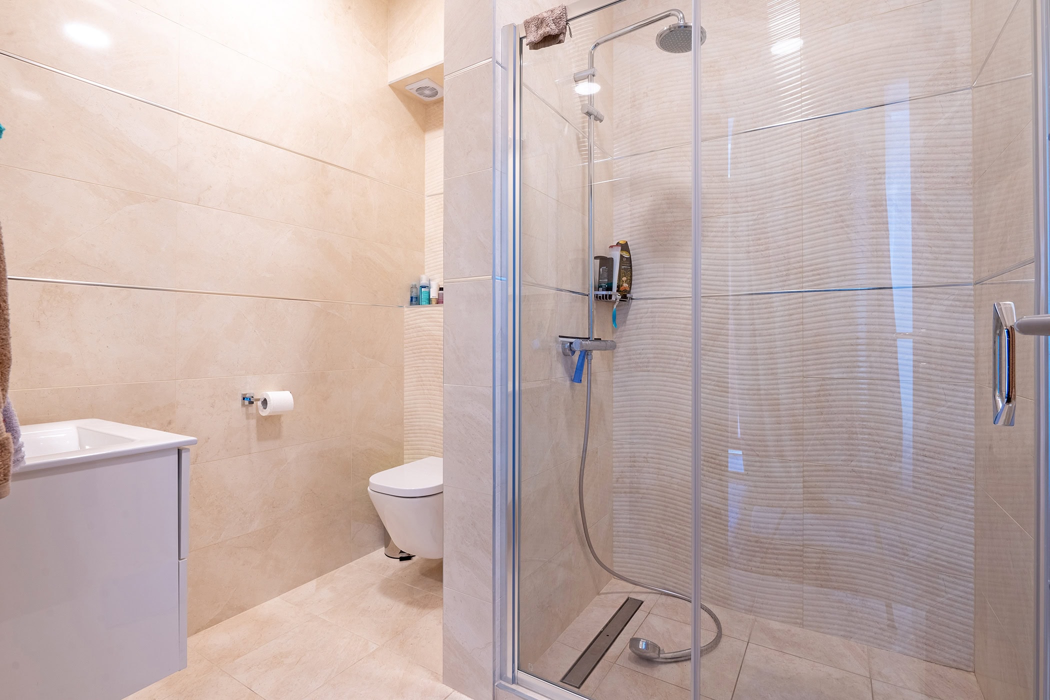 Modernes Badezimmer mit Duschkabine und hellen Fliesen in einer Wohnung in Budva, Montenegro.