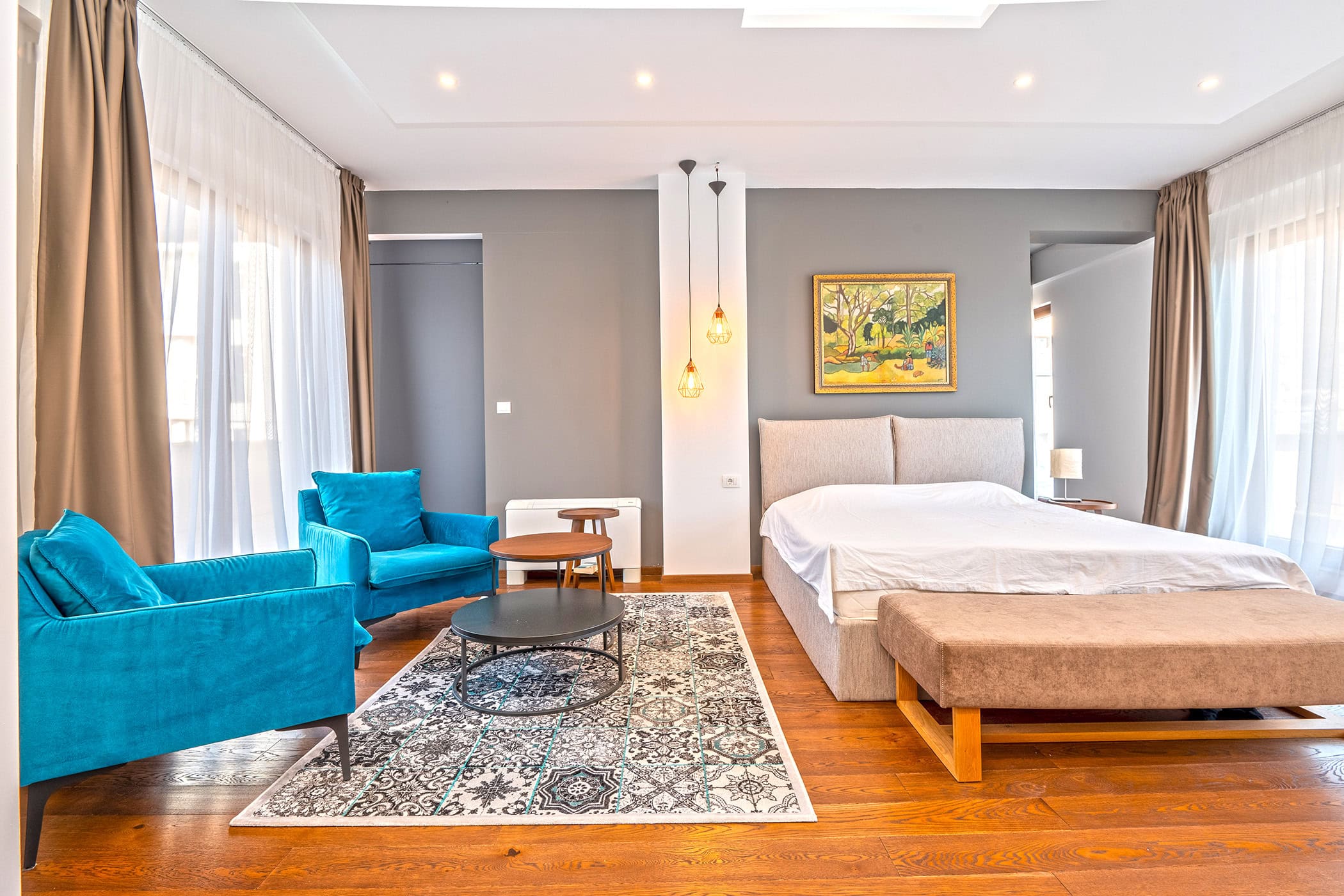 Modernes Schlafzimmer in einer Wohnung in Budva, Montenegro: Doppelbett, blaue Sessel, Parkett und Panoramafenster.