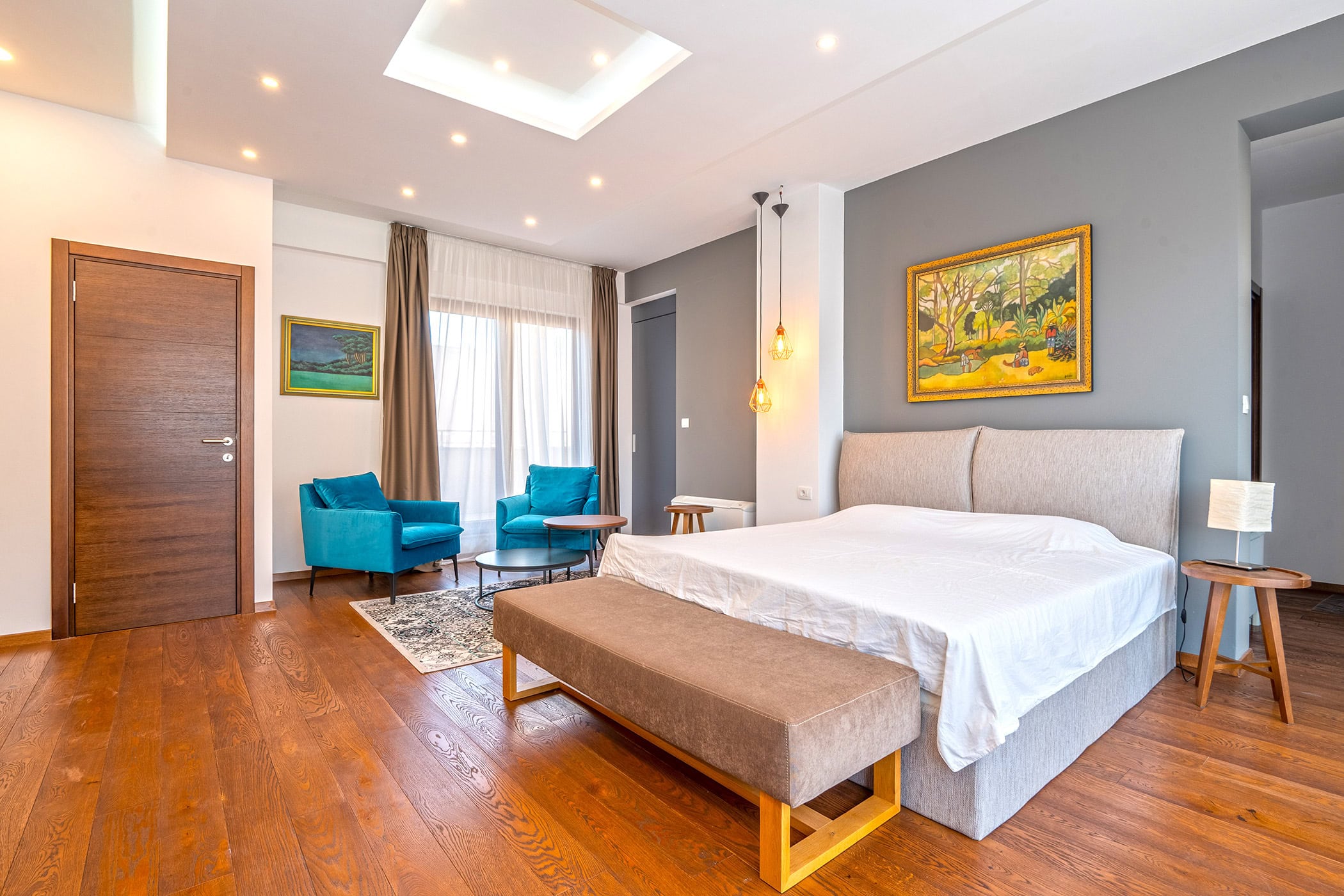 Modernes Schlafzimmer in einer Wohnung in Budva, Montenegro: Doppelbett, blaue Sessel, Holzboden und stilvolle Dekoration.