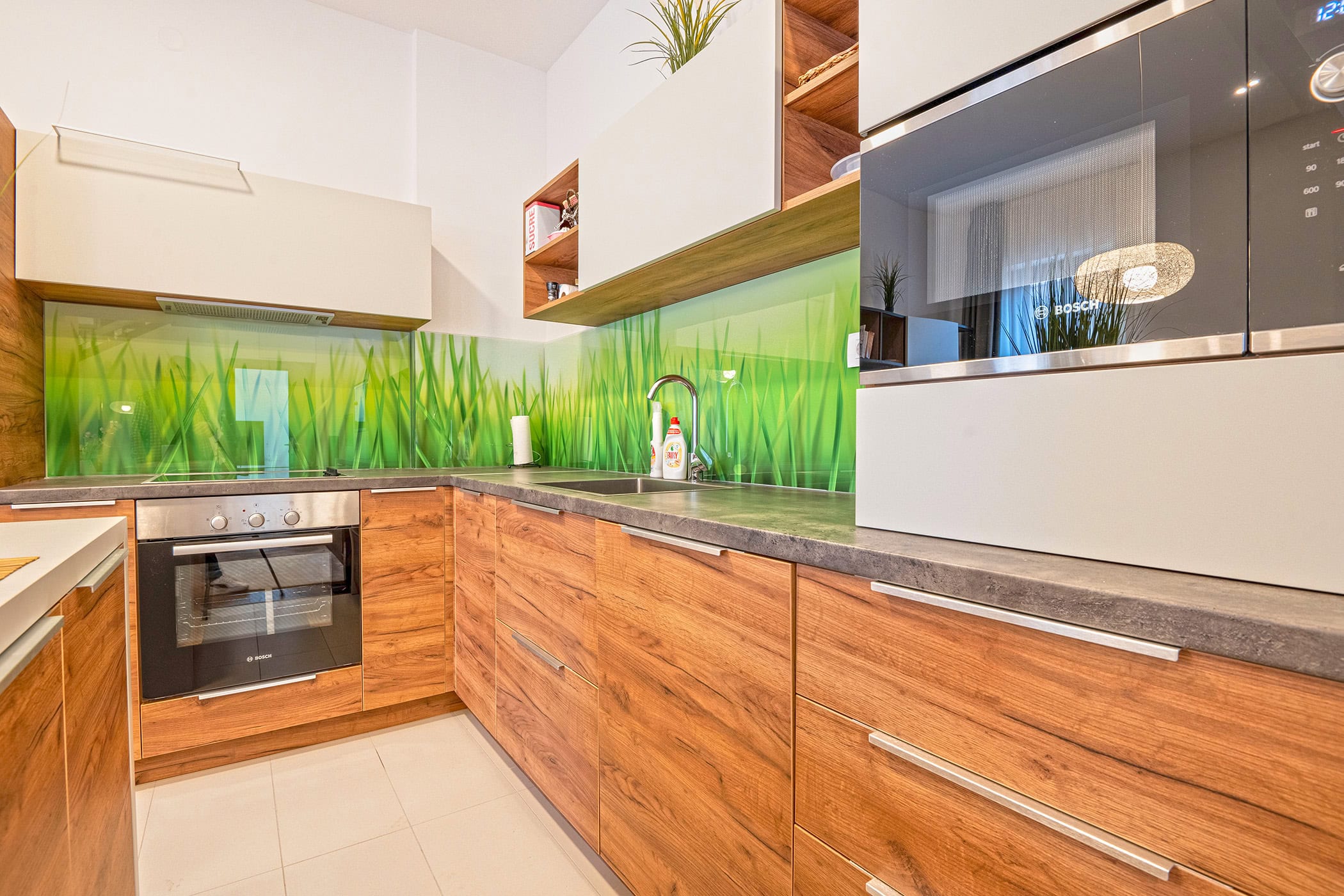 Moderne Küche mit Holzfronten und einer Rückwand mit Gras in einer Wohnung in Budva, Montenegro, Bosch-Geräte.