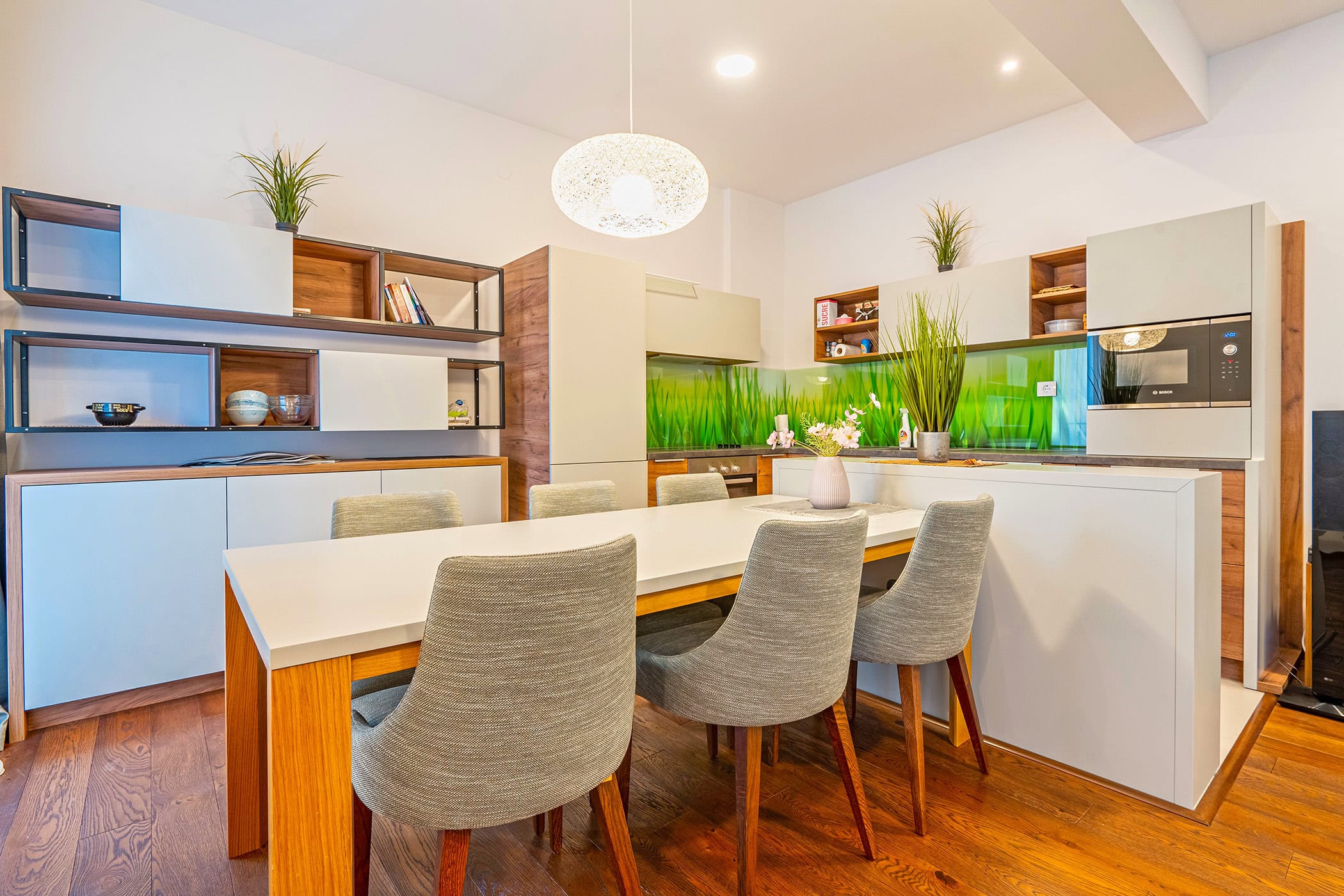 Moderne Wohnküche in einer Wohnung in Budva, Montenegro: helle Küchenzeile, Esstisch und stilvolle Dekoration.