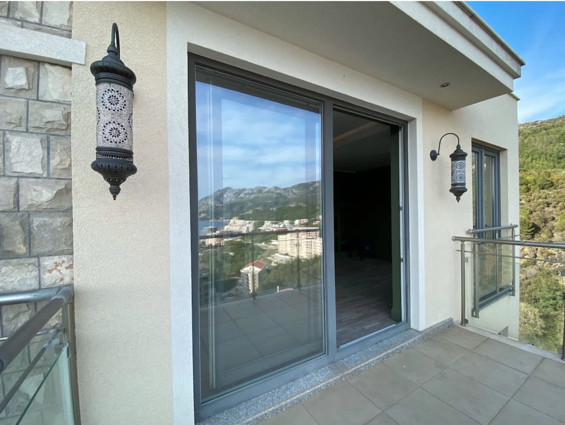 Balkon mit Panoramablick auf Berge und Meer in der Wohnung, Bečići, Montenegro: stilvolle Wandleuchten und Verglasung.