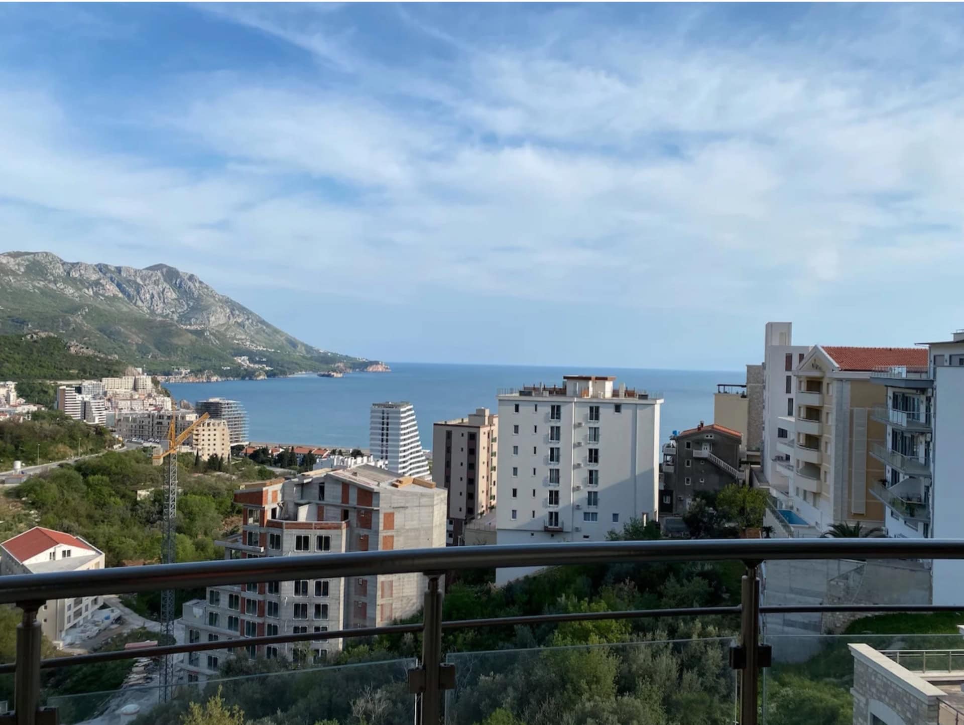 Panoramablick auf das Meer und die Berge vom Balkon der Wohnung in Bečići, Montenegro, mit Blick auf die Stadtbebauung und die Küste.