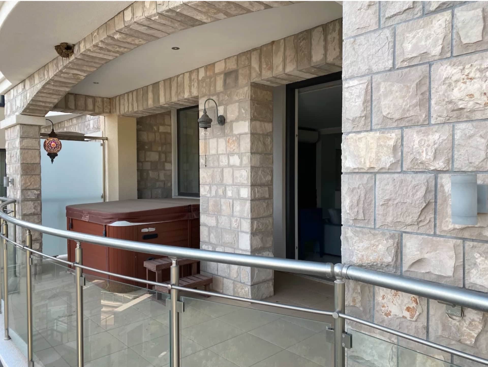 Terrasse mit Jacuzzi in einer Wohnung in Bečići, Montenegro: Natursteinverkleidung, Glasgeländer und Dekor.