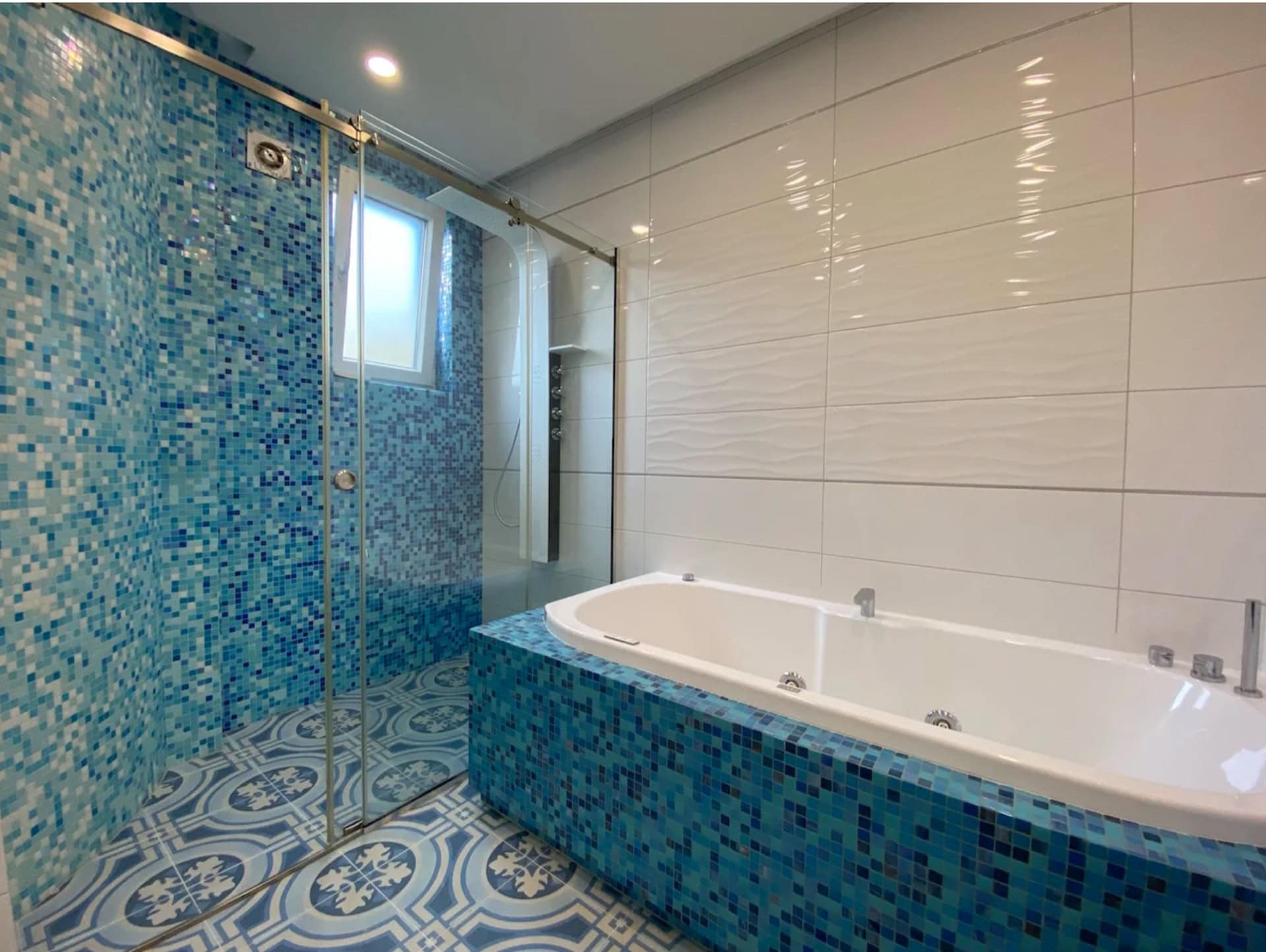Modernes Badezimmer mit Whirlpool und Duschkabine in einer Wohnung in Bečići, Montenegro: mit blauer Mosaikverkleidung.