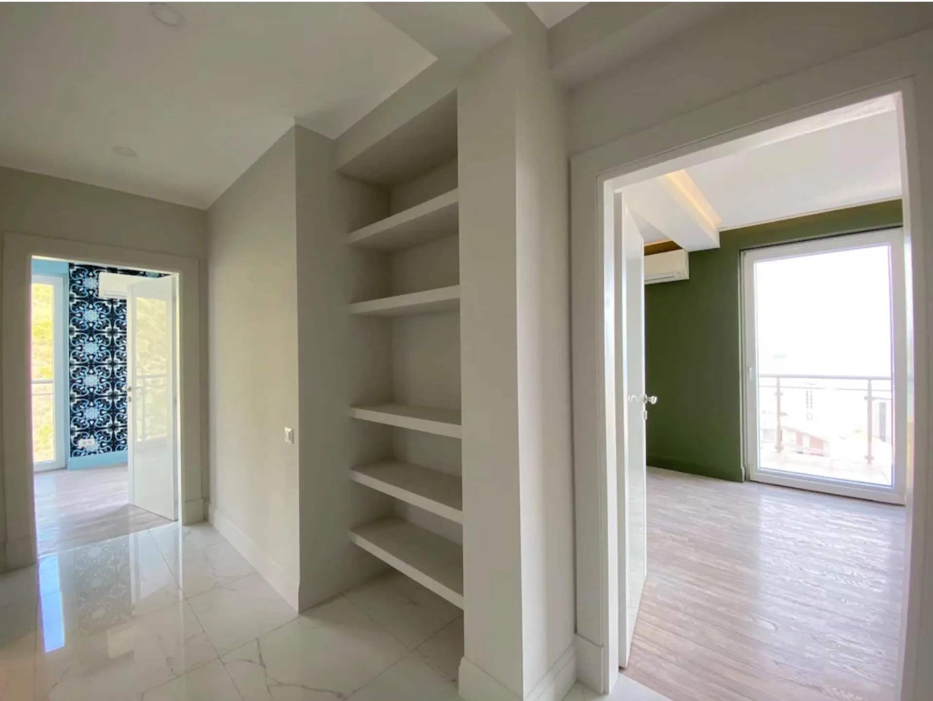 Apartment interior in Bečići, Montenegro: a bright hallway with built-in shelves and access to rooms with panoramic windows.