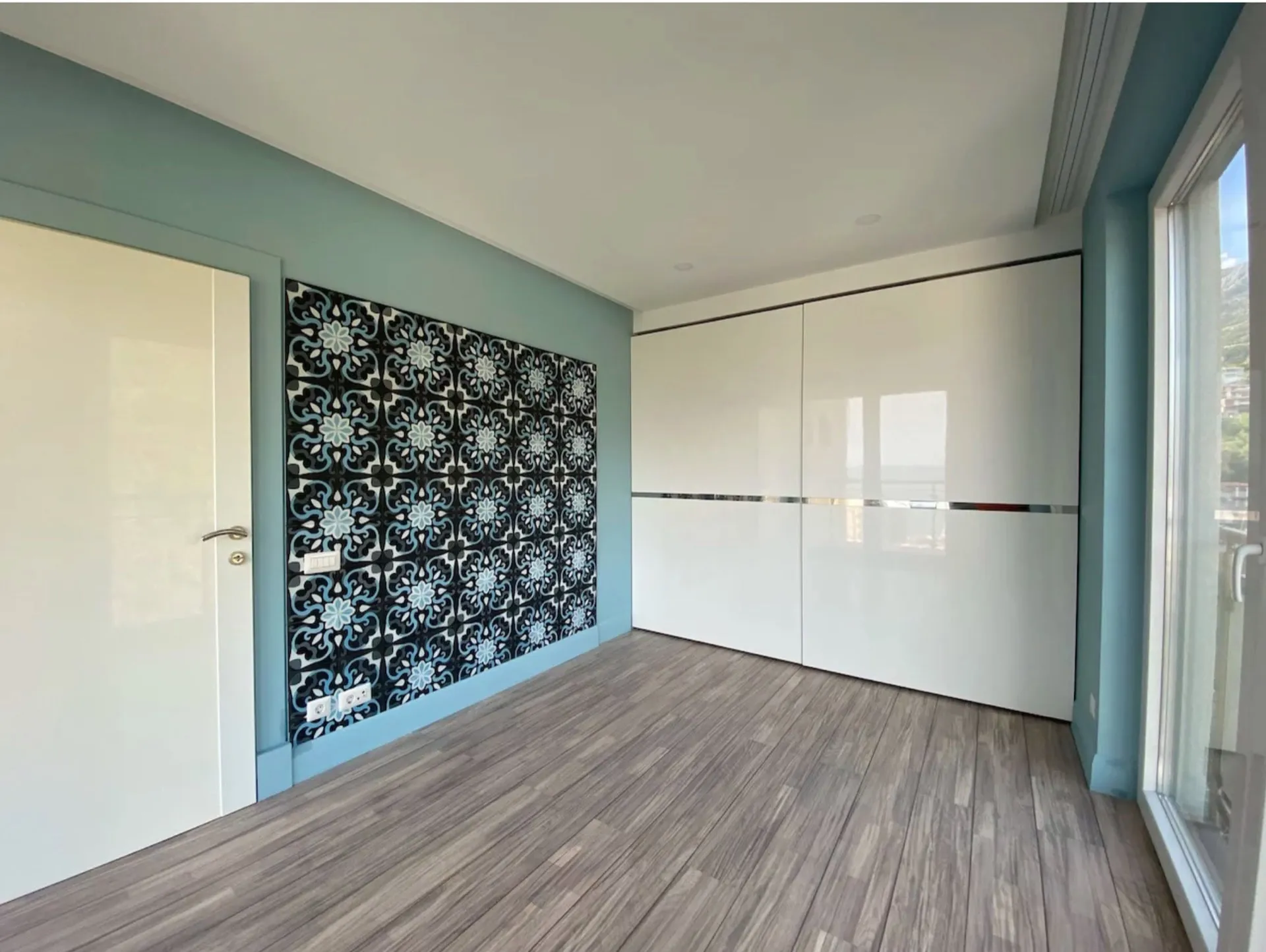 Bright bedroom with a white sliding wardrobe and an accent wall in an apartment in Bečići, Montenegro. Modern interior.