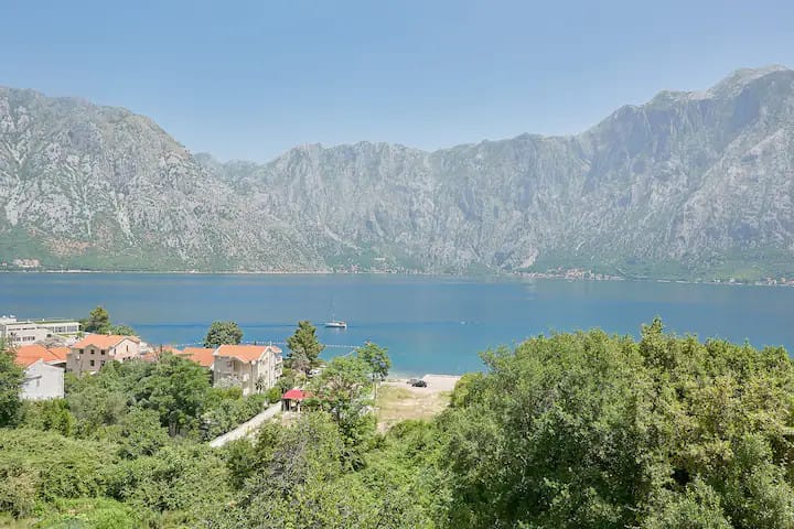 Karadağ, Prčanj’deki daireden Kotor Körfezi ve dağların panoramik manzarası: deniz, yatlar ve yeşil kıyı bölgesi.