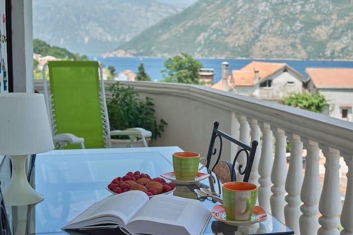 Kotor Körfezi manzaralı balkon, Prčanj, Karadağ: cam masa, fincanlar, meyveler ve şezlong.