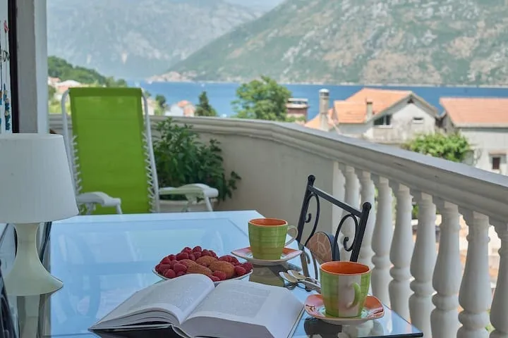 Kotor Körfezi manzaralı balkon, Prčanj, Karadağ: cam masa, fincanlar, meyveler ve şezlong.