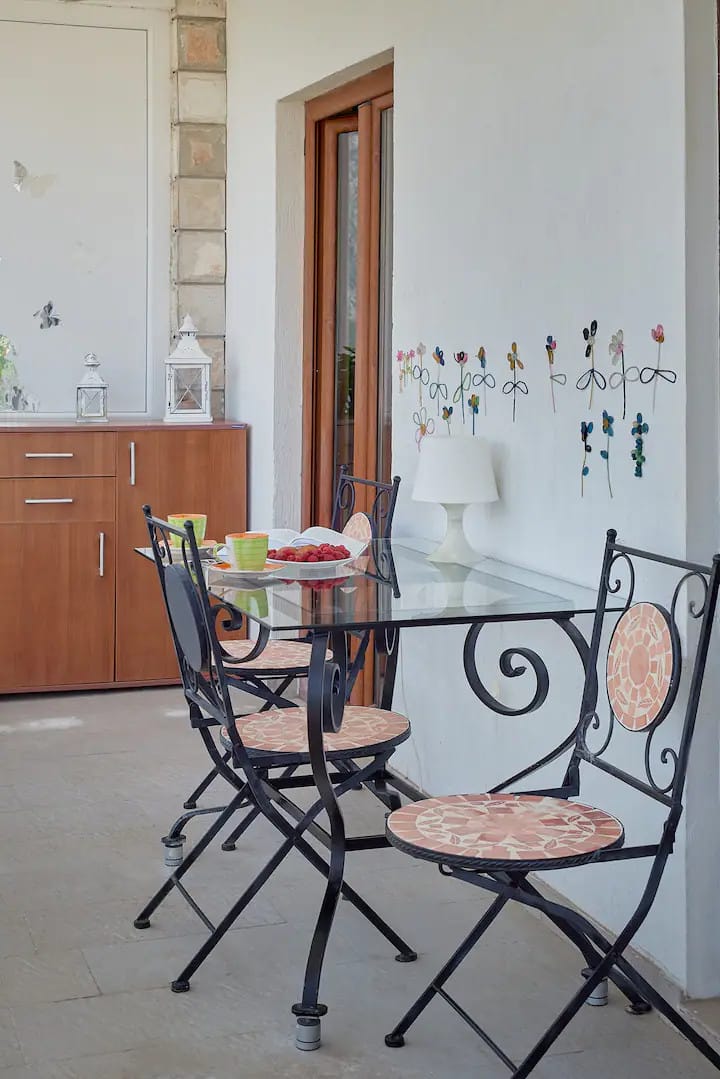 Dövme mobilyalı ve mozaik dekorlu уютный balkon, Prčanj, Karadağ. Terasta kahvaltılı küçük masa.
