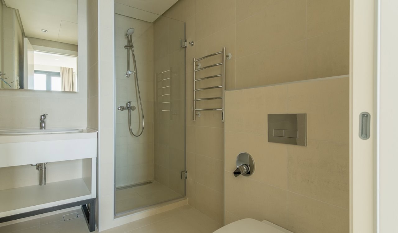 Modernes Badezimmer mit Dusche und weißen Möbeln in einer Wohnung in Bečići, Montenegro