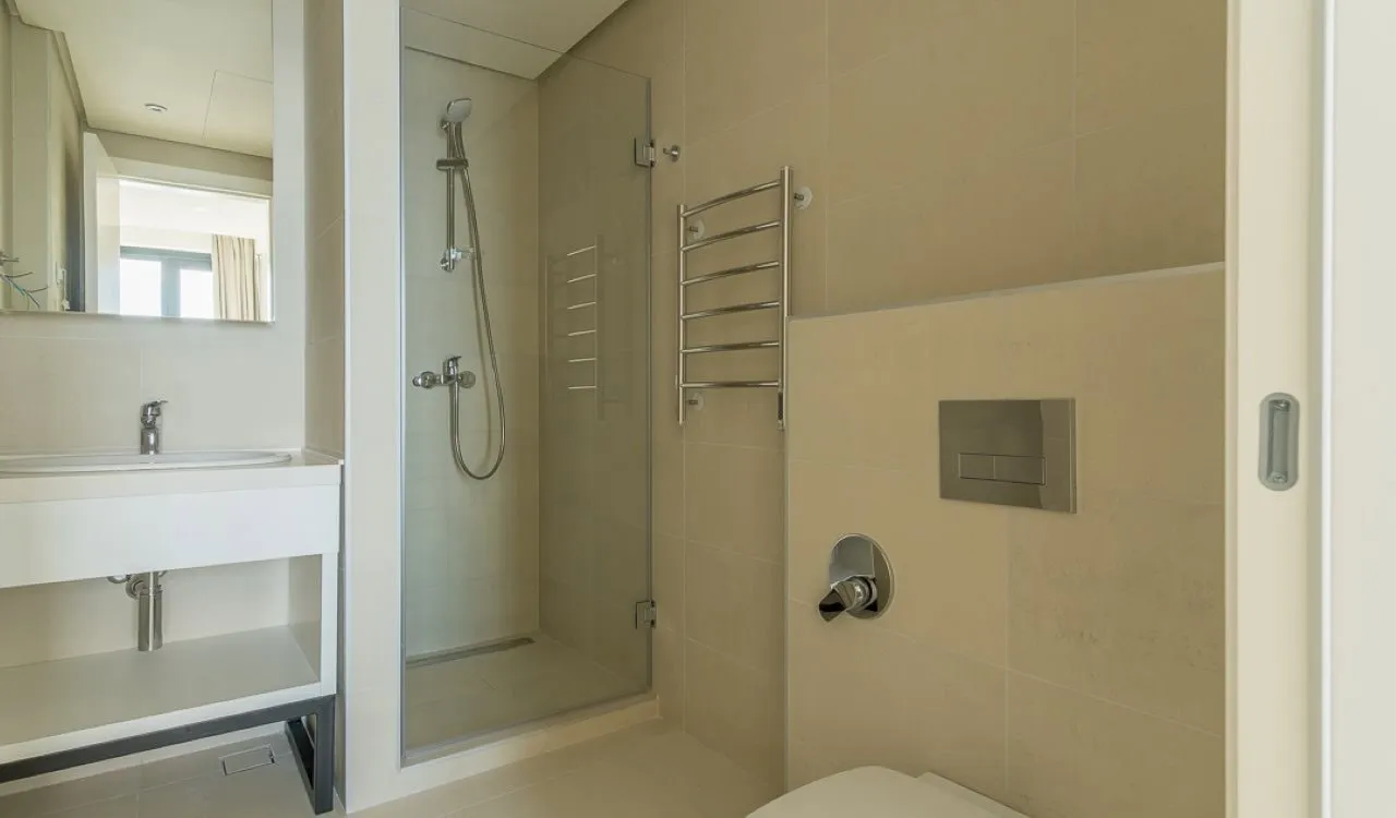 Modern bathroom with a shower cabin and white furniture in apartments in Bečići, Montenegro