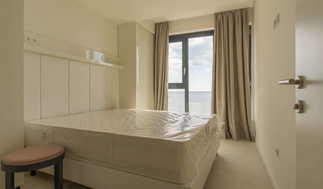 Helle Schlafzimmer mit neuen Möbeln und Panoramafenster in einer Wohnung in Bečići, Montenegro.