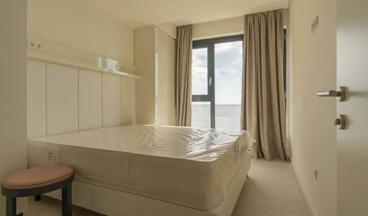 Bright bedroom with new furniture and a panoramic window in an apartment in Bečići, Montenegro.