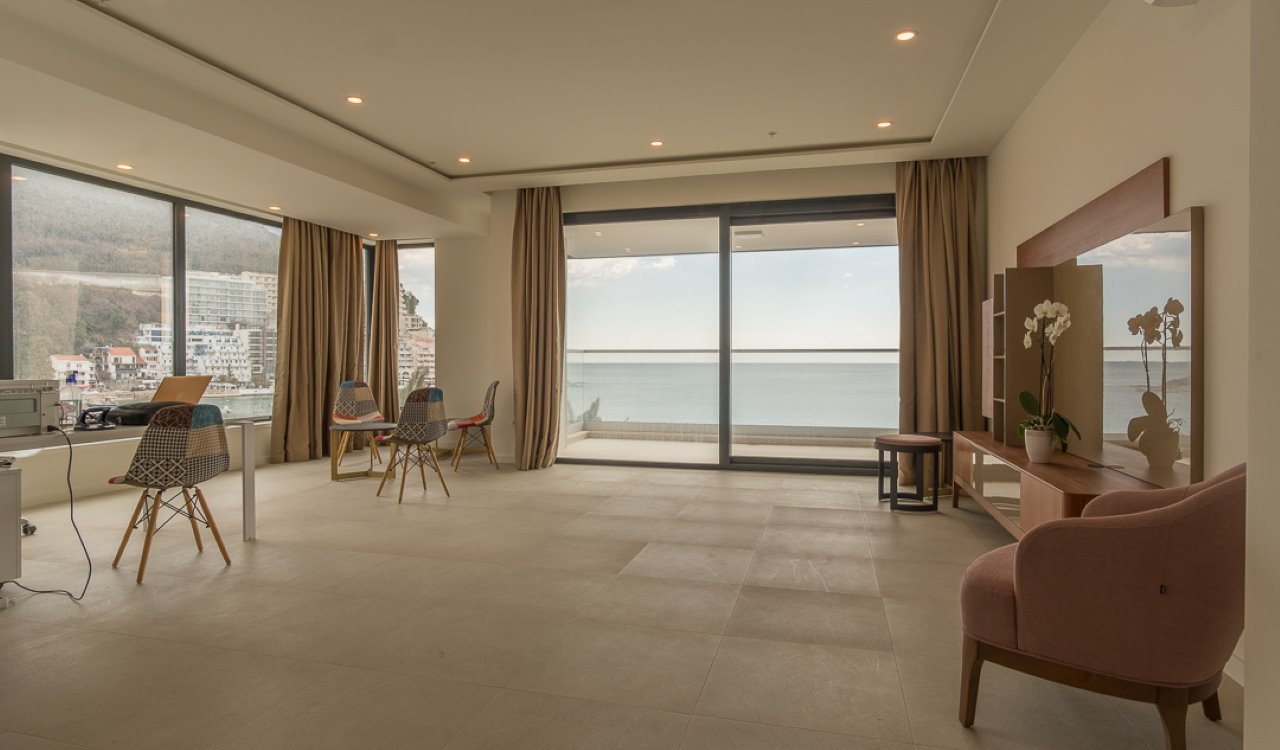 Geräumiges Wohnzimmer mit Panoramafenstern, Möbeln und Meerblick in einer Wohnung in Bečići, Montenegro