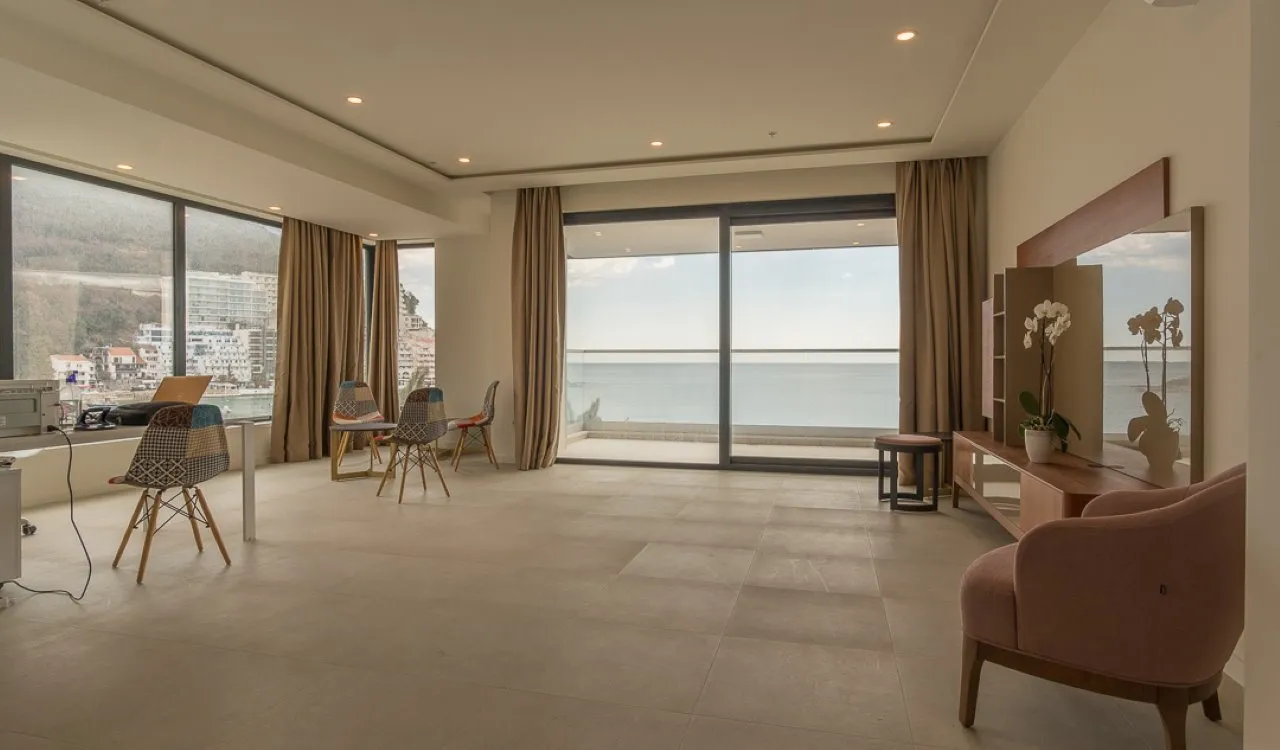 Spacious living room with panoramic windows, furniture, and sea view in an apartment in Bečići, Montenegro.