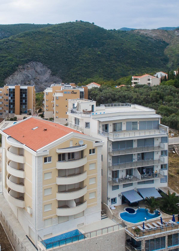 Moderne Wohnanlagen mit Pools in Bečići, Budva-Riviera, Montenegro: Blick auf Häuser und Berge.