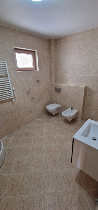 Modernes Badezimmer in einer Wohnung in Bečići, Montenegro: Hänge-WC, Bidet, beige Fliesen und Fenster.