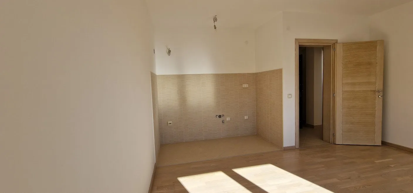 Kitchen area in an apartment in Bečići, Montenegro: light finishes, tiled backsplash, parquet flooring, and an interior door.