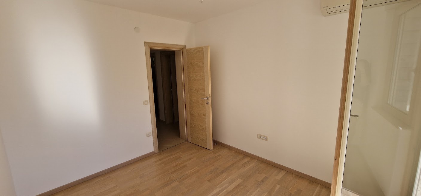 Helles Schlafzimmer mit Parkett und Innentür in einer Wohnung in Bečići, Budva-Riviera, Montenegro.