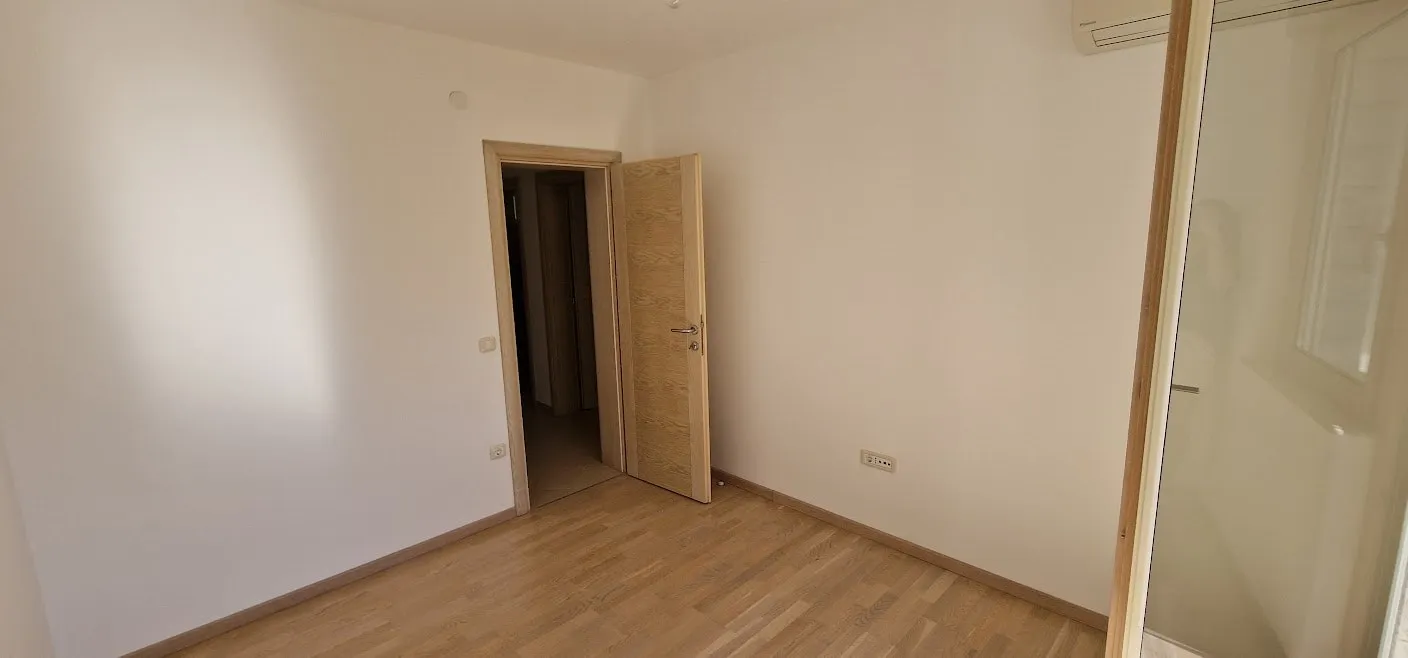 Bright bedroom with parquet flooring and an interior door in an apartment in Becici, Budva Riviera, Montenegro.