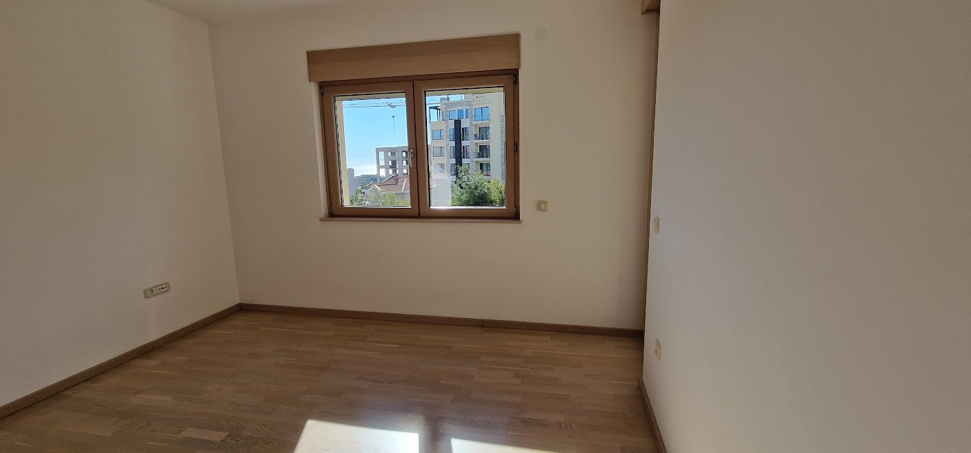 Helles Schlafzimmer mit Parkettboden und Blick auf die Stadt in einer Wohnung in Bečići, Budva-Riviera, Montenegro.