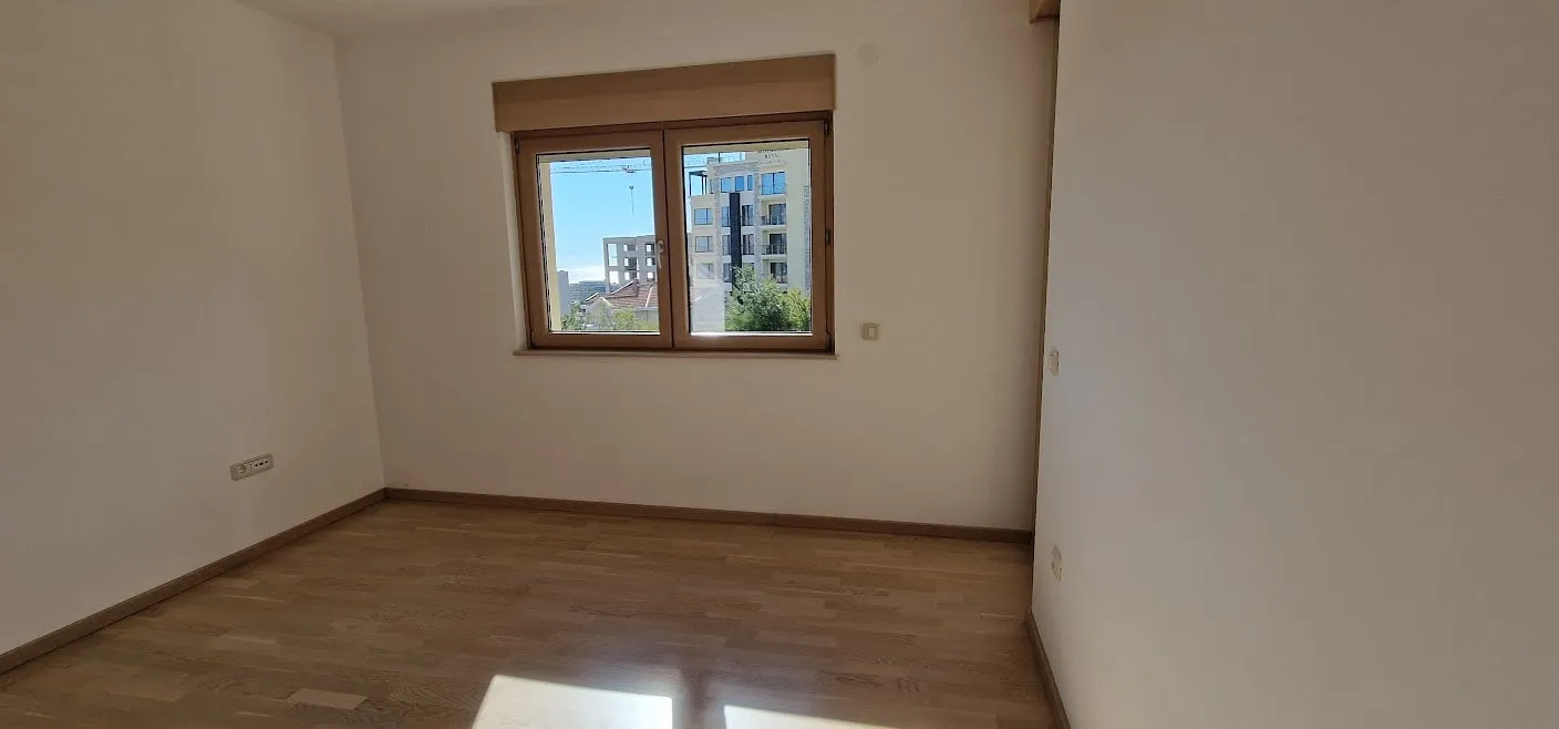 Bright bedroom with parquet flooring and city view in an apartment in Becici, Budva Riviera, Montenegro.
