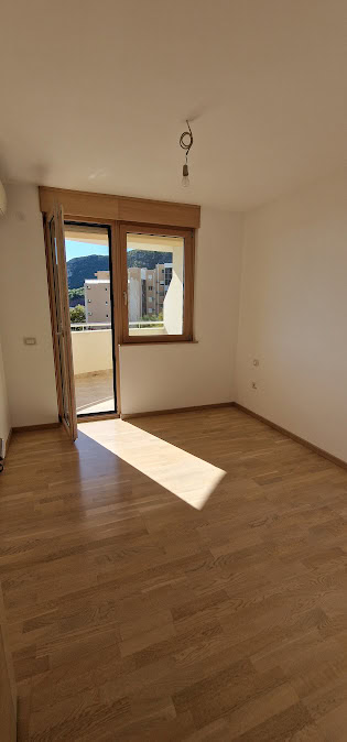 Helles Schlafzimmer mit Parkett und Zugang zum Balkon in einer Wohnung in Bečići, Budva-Riviera, Montenegro.
