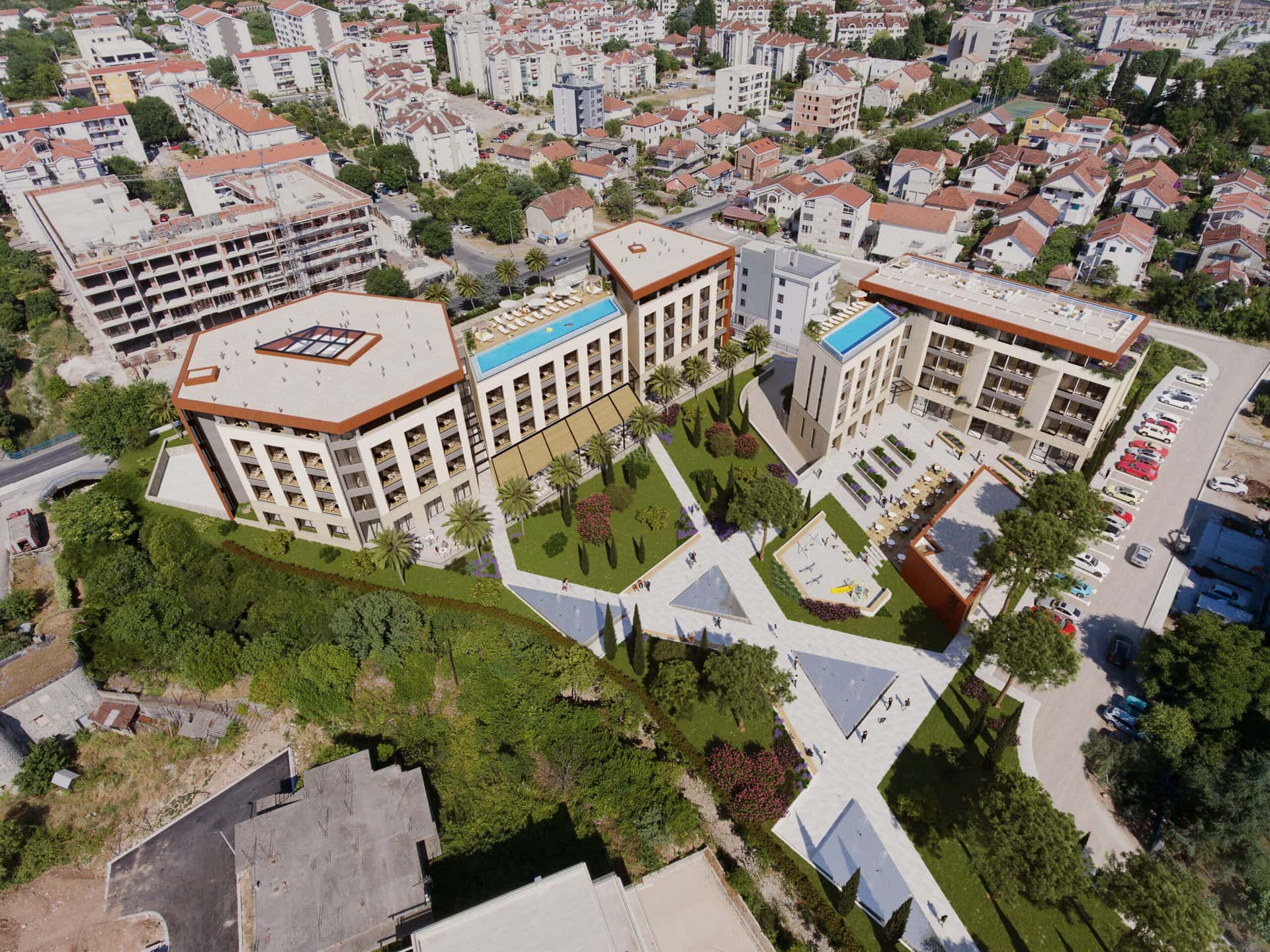Pogled odozgo na stambeni kompleks u Tivtu, Crna Gora: moderne zgrade sa bazenima na krovu i uređenim dvorištem.