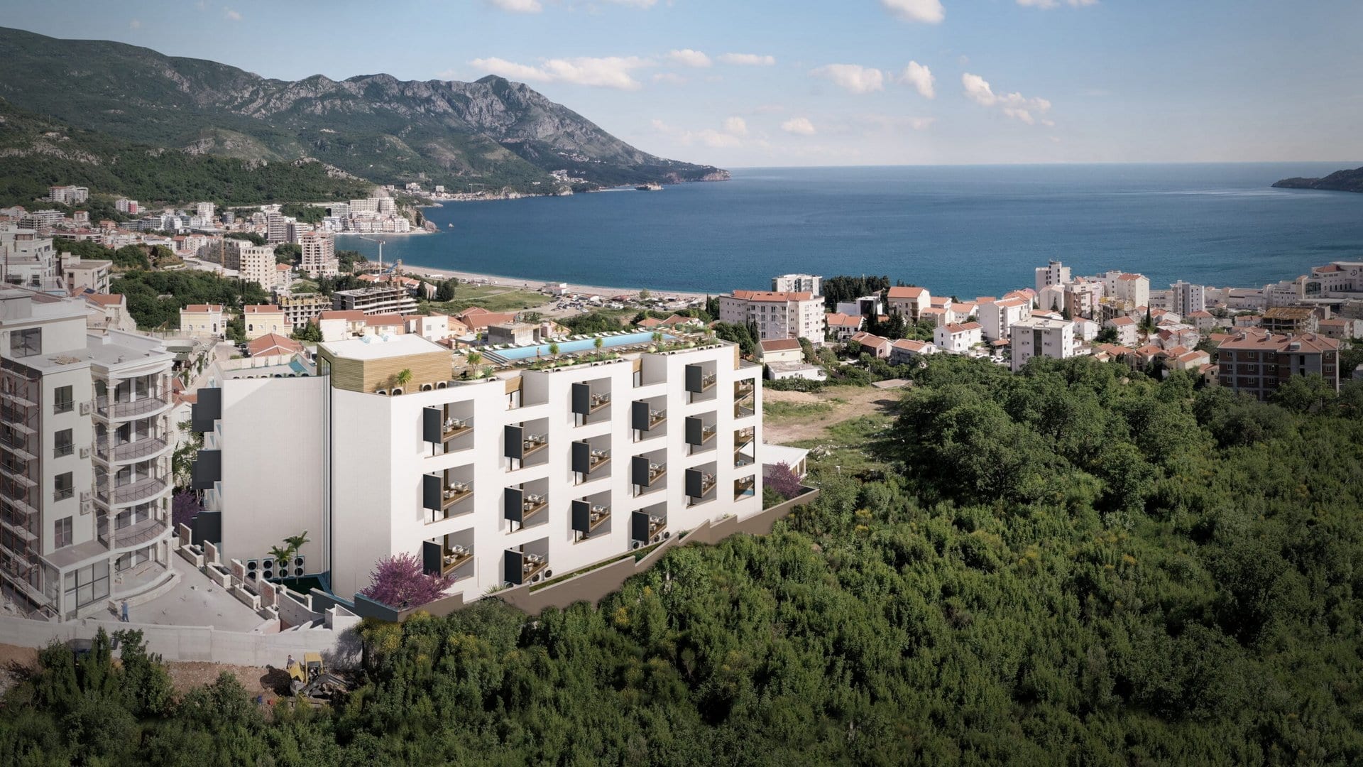 Karadağ, Bečići’de yeni konut kompleksi: çatıda havuzlu ve panoramik deniz manzaralı modern bina.