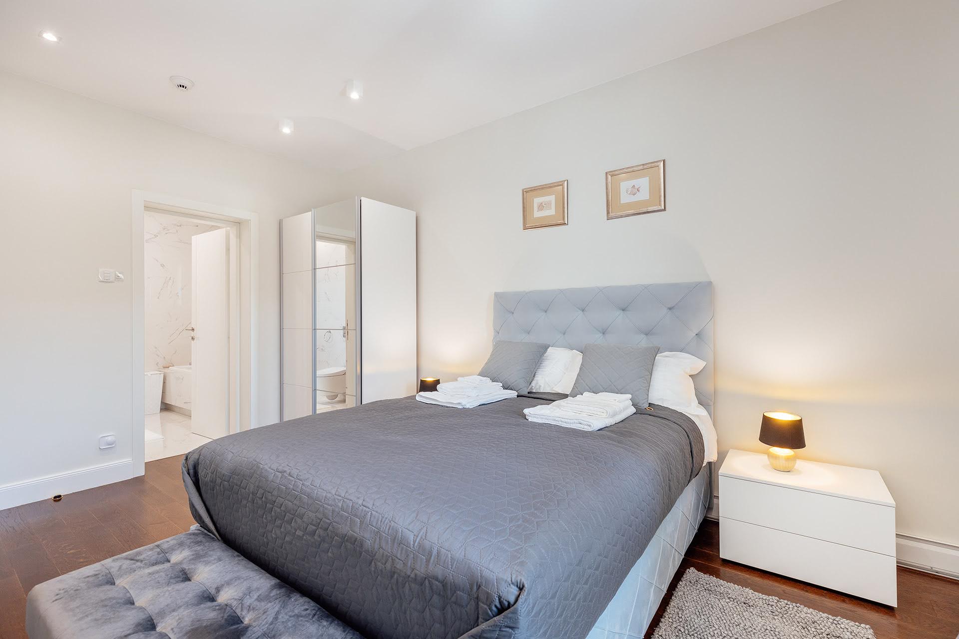 Modernes Schlafzimmer mit Doppelbett und Badezimmer im ЖК Kumbor, Montenegro. Helles Interieur, Parkett.