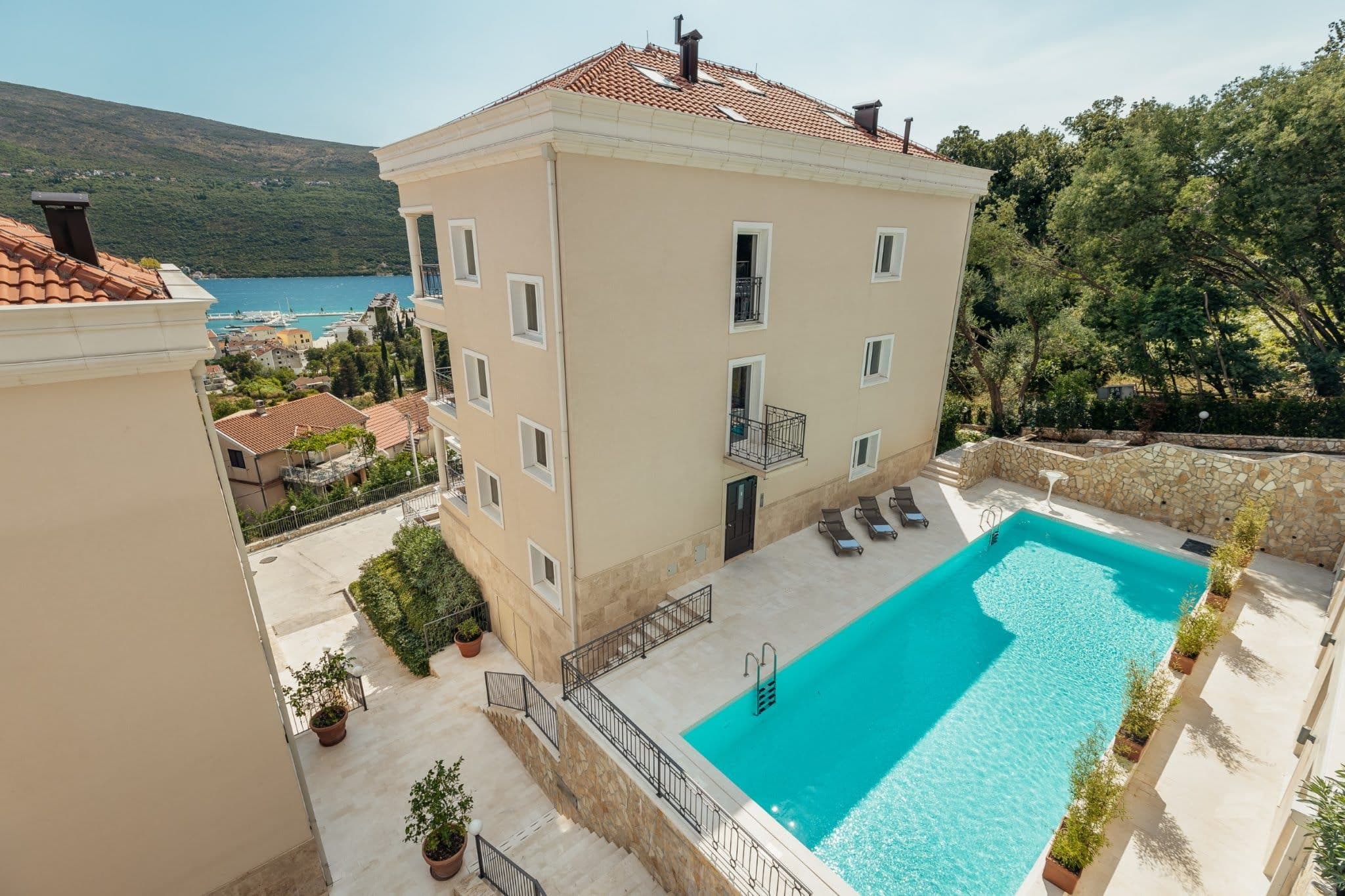 Wohnanlage in Kumbor, Montenegro: Blick auf das Gebäude mit Pool, Terrasse und Panoramablick auf das Meer und die Berge.